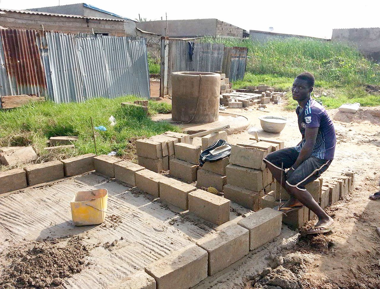 An unidentified man takes a break while working on a compost toilet for a family living in the village of Zogbedgi, Togo. Eight compost toilets have been built in the past two years, with plans to build 10 more. (Bedi Taouvik Boukari)