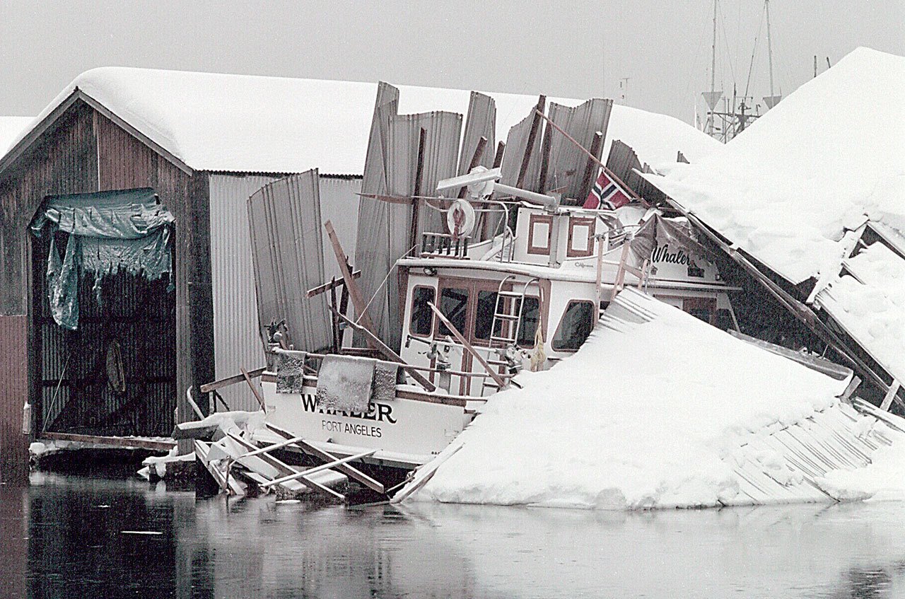 A boat lists under the weight of a collapsed boathouse at Port Angeles Boat Haven on Dec. 29, 1996. Heavy snow from a storm that began the day before, combined with the weight of rain, caved in numerous structures across the North Olympic Peninsula. (Keith Thorpe/Peninsula Daily News)