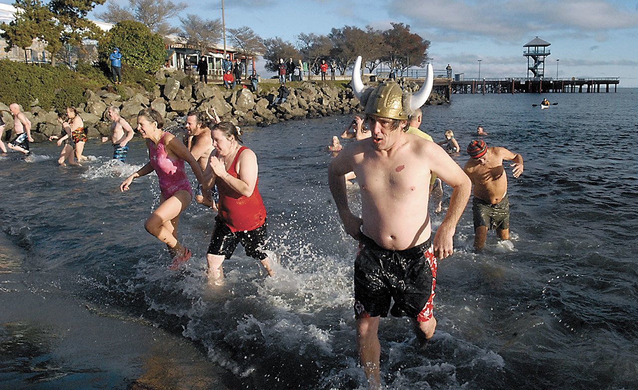 Chris Fowler of Port Angeles, wearing a viking hat, emerges from the chilly waters of Port Angeles Harbor with dozens of other people during the 2016 polar bear plunge in honor of the new year. (Keith Thorpe/Peninsula Daily News)