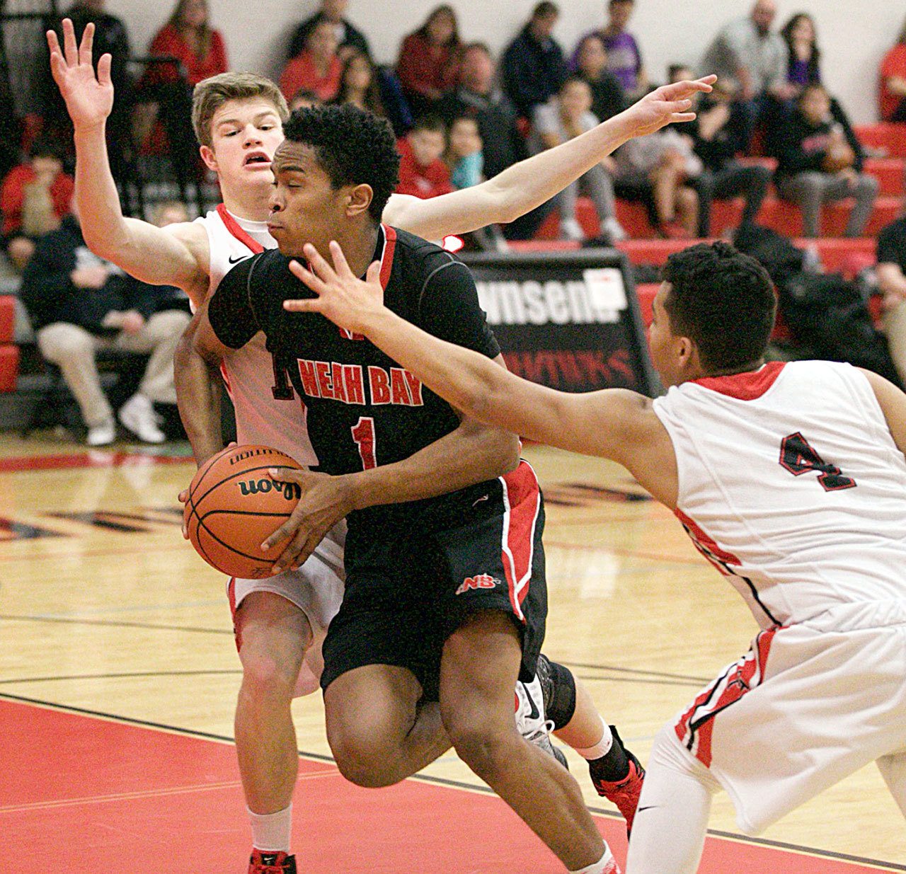 Steve Mullensky/for Peninsula Daily News Neah Bay’s Rweha Munyagi blasts through the defense put up by Redhawks Berkley Hill and Jacob Boucher, 4, during a Crush in the Slush game played at Port Townsend High School on Friday.