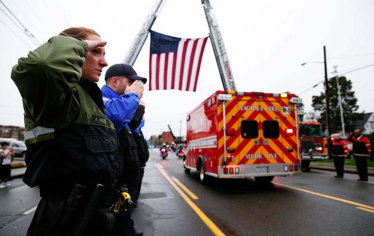 Tacoma Police Department animal control officer Kate Madden salutes during the procession for Tacoma Police Officer Reginald &ldquo;Jake&rdquo; Gutierrez on Friday in Tacoma. Crowds gathered to pay respects to Gutierrez, who died Wednesday after being shot while responding to a domestic violence call. (Erika Schultz/The Seattle Times via AP)