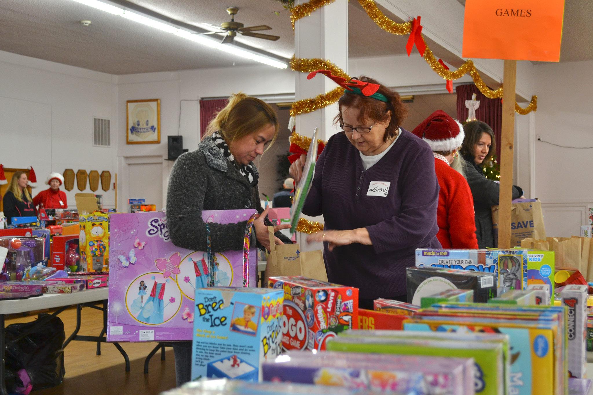 Farah Durham of Sequim looks for toys for her 4-year-old daughter with help from volunteer Gisele Gala at Toys for Sequim Kids on Dec. 14 in the Sequim Prairie Grange. “It’s a blessing to help others because God has blessed us so abundantly,” Gala said. (Matthew Nash/Olympic Peninsula News Group)