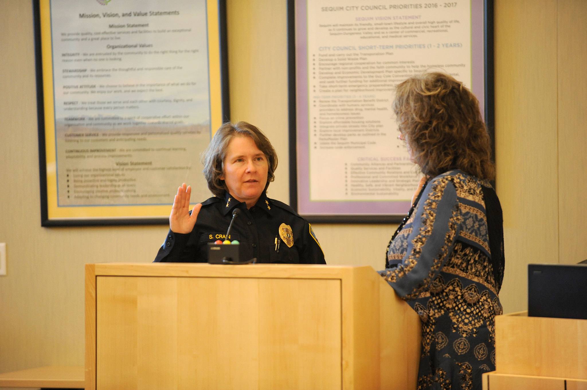 Matthew Nash/Olympic Peninsula News Group                                Sheri Crain, new police chief for the city of Sequim, takes an oath for the position from Sequim city clerk Karen Kuznek-Reese last Friday in the Sequim City Council’s chambers.