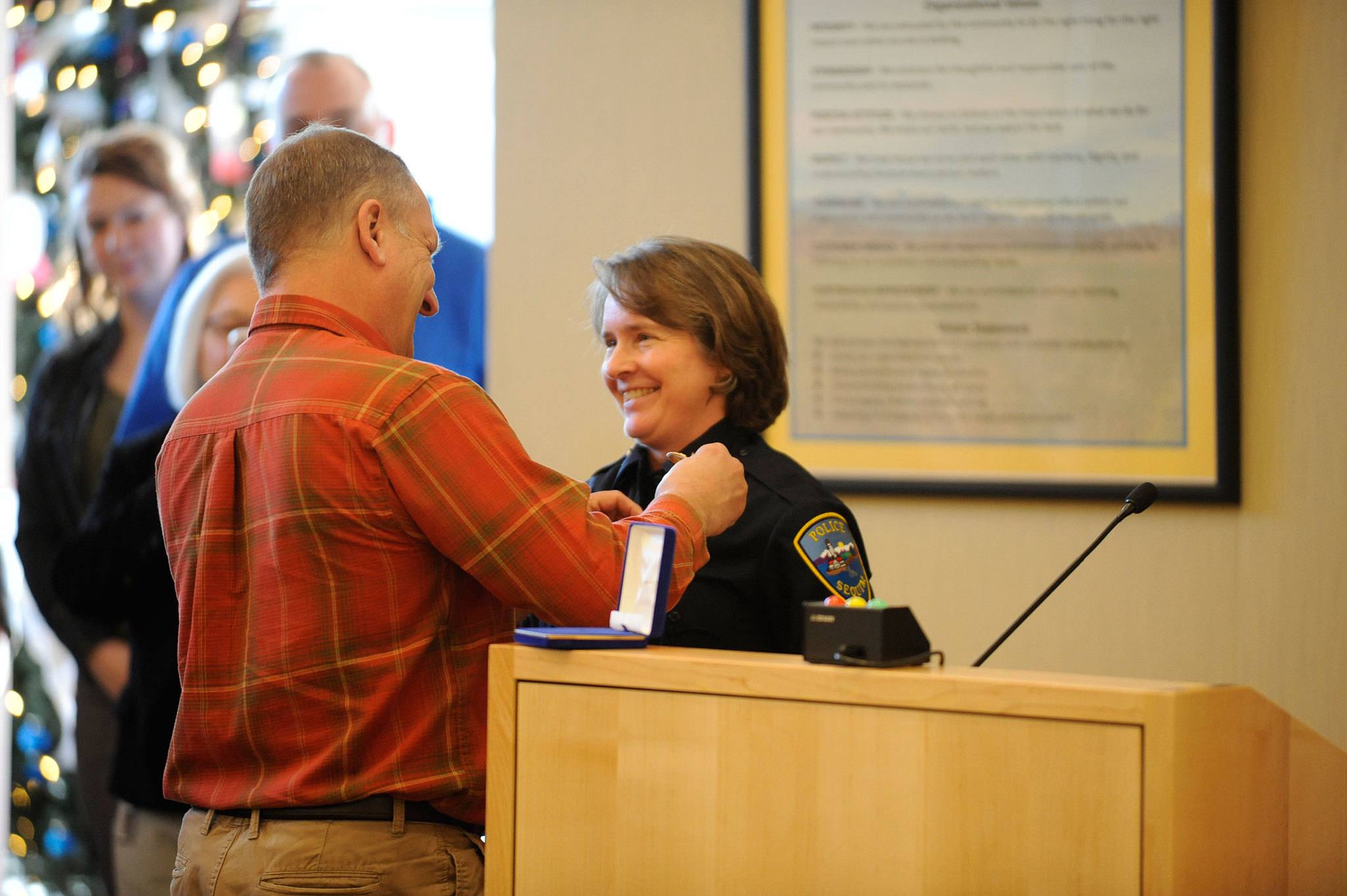 Pat Crain pins the Sequim police chief badge on his wife Sheri Crain on Friday, Dec. 16, after she was sworn into the position. Sequim Gazette photo by Matthew Nash