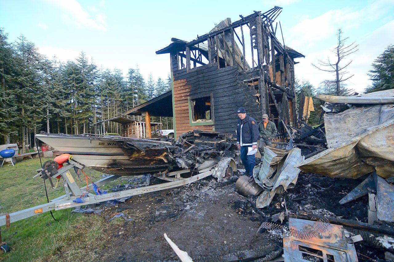 Firefighters searched Monday for the cause of a fire that destroyed a Carlsborg home on New Year’s Day. (Jesse Major/Peninsula Daily News)