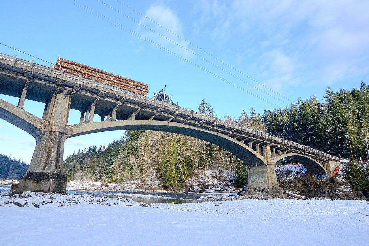 A logging truck passes over the Elwha River bridge on U.S. Highway 101 on Tuesday. (Jesse Major/Peninsula Daily News)
