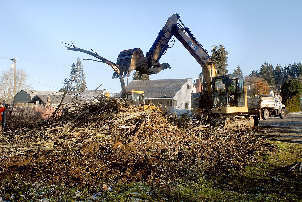 An excavator piles brush pulled from the banks of Peabody Creek near Ninth Street in Port Angeles on Wednesday to gain access to a broken water main beneath the creek bed. (Keith Thorpe/Peninsula Daily News)