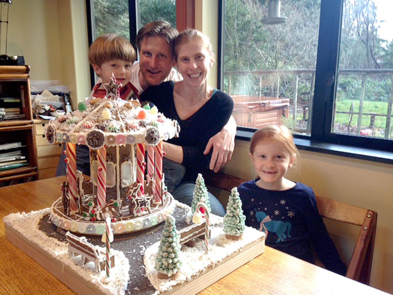 Eric and Holly Kuzma, with their son Cabett and daughter Anora, display their gingerbread house that won this year.