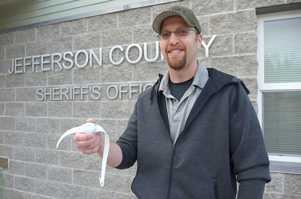 Jefferson County Sheriff’s Office Detective Brett Anglin holds one of the devices used in Project LifeSaver to help law enforcement track people with cognitive disorders should they wander from their caregivers. (Cydney McFarland/Peninsula Daily News)