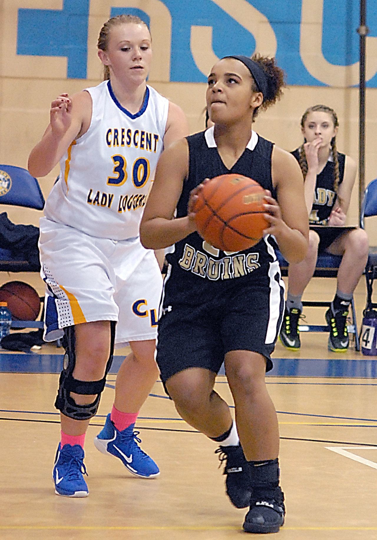 Keith Thorpe/Peninsula Daily News Clallam Bay’s Atokena Abe, right, drives to the lane past Crescent’s Alyssa Hutto in the fourth quarter on Friday night in Joyce.