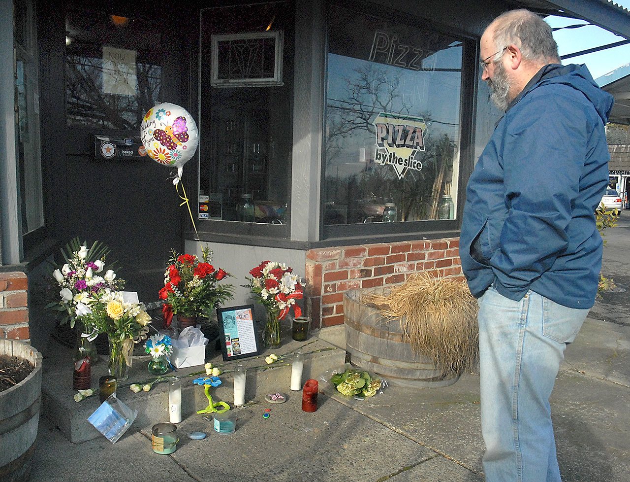 Pete Rennie of Port Angeles, a former patron of Van Goes Gourmet Pizza & Mexican, pays his respects at a make-shift shrine to restaurant-owner Clint Darrow at the front door of the Port Angeles business on Saturday. (Keith Thorpe/Peninsula Daily News)