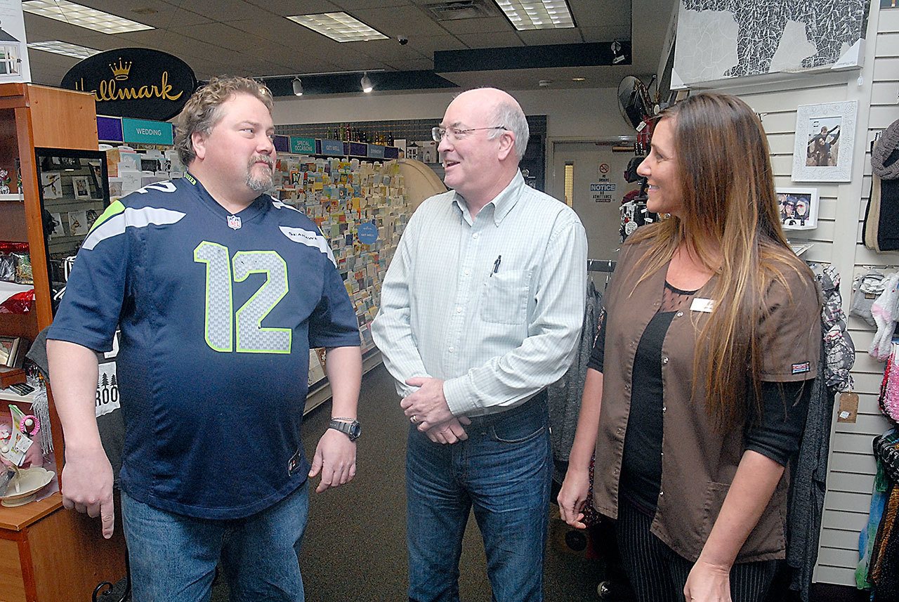 Peninsula Daily News General Manager Steve Perry, center, talks with Jim’s Pharmacy owner Joe Cammack, left, and Chief Operations Officer Lisa Jorgensen after Perry received a check for $519.32 to the Peninsula Home Fund on Friday at the Port Angeles pharmacy. (Keith Thorpe/Peninsula Daily News)