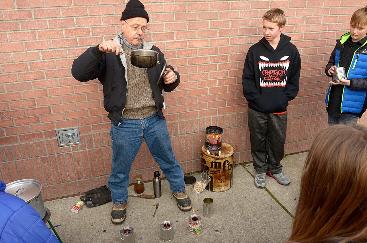 Devin Jensen and his mentor through the YMCA, Francesco Tortorici, hold a demonstration on stoves at Blue Heron Middle School. (Cydney McFarland/Peninsula Daily News)