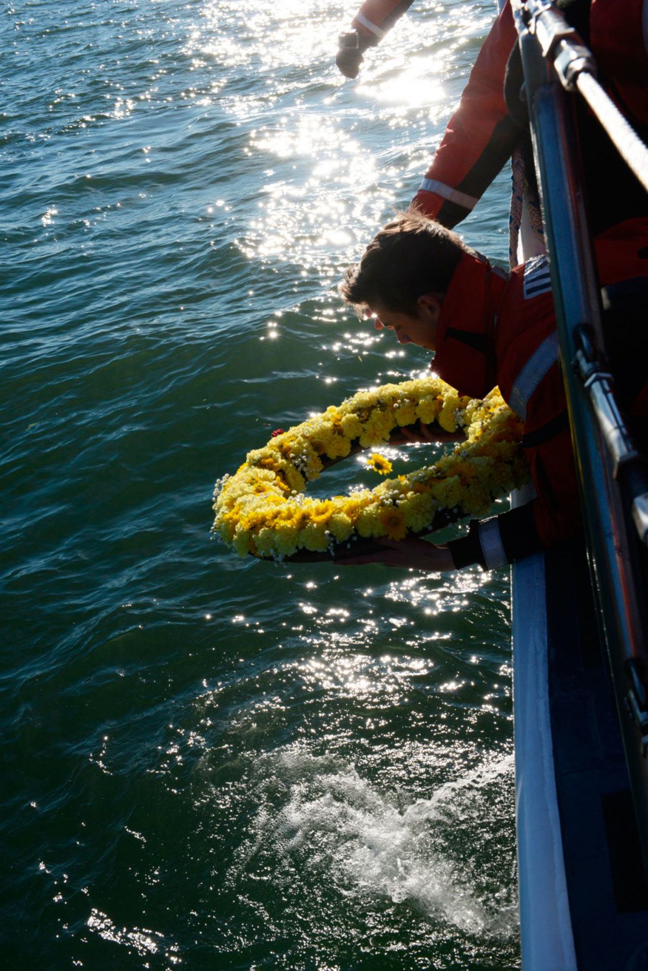 Boatswain’s Mate Third Class Austin Kettleson, from Coast Guard Station Cape Disappointment, places a memorial wreath into the Pacific Ocean near the North Head Light in Ilwaco during a memorial ceremony Saturday. (Kaitlin Florez/U.S. Coast Guard)