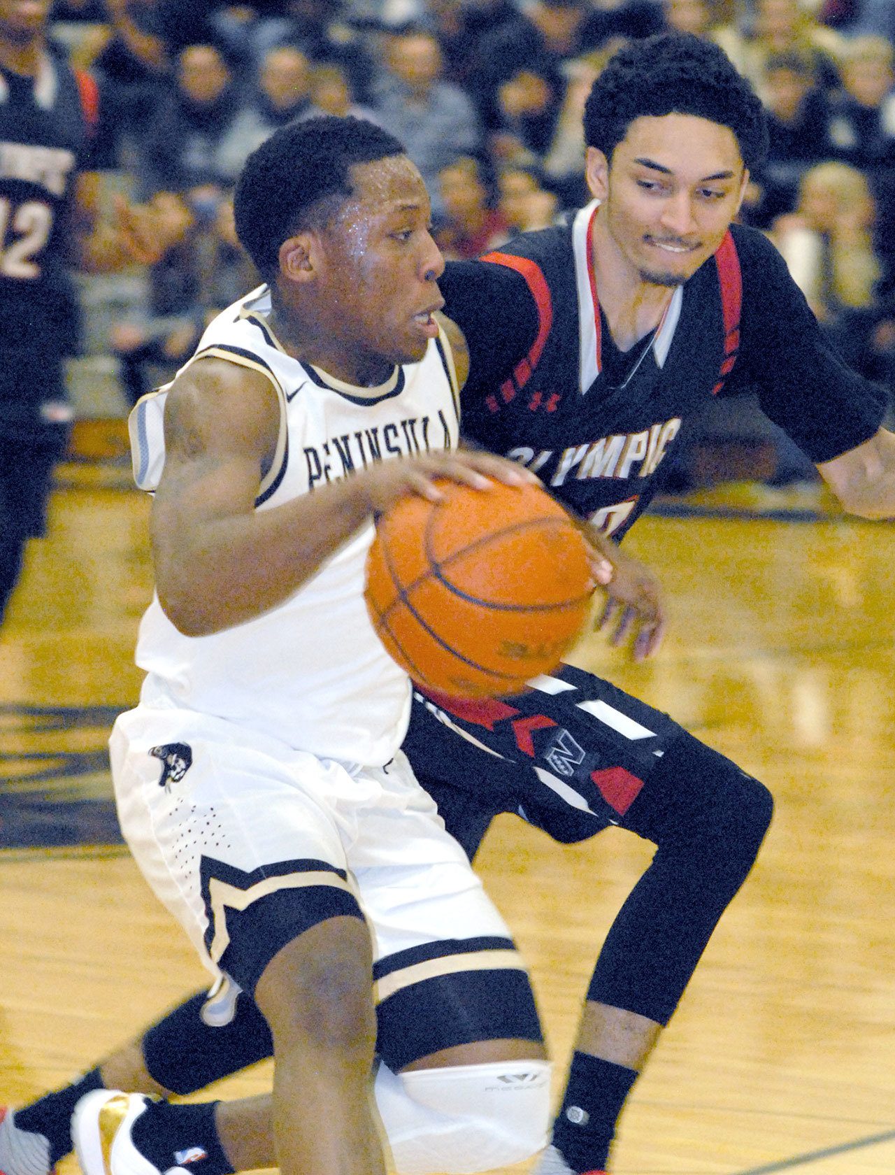 Keith Thorpe/Peninsula Daily News Peninsula’s Darrion Daniels, left, slips around Olympic’s JonRoss Juhas in first half play in Port Angeles on Wednesday night.