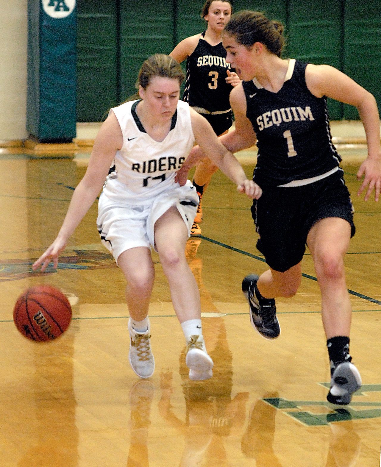 Keith Thorpe/Peninsula Daily News Port Angeles’ Lauren Lunt drives down court with Sequim’s Hope Glasser in second-quarter play on Friday. Following behind is Sequim’s Bobbi Sparks.