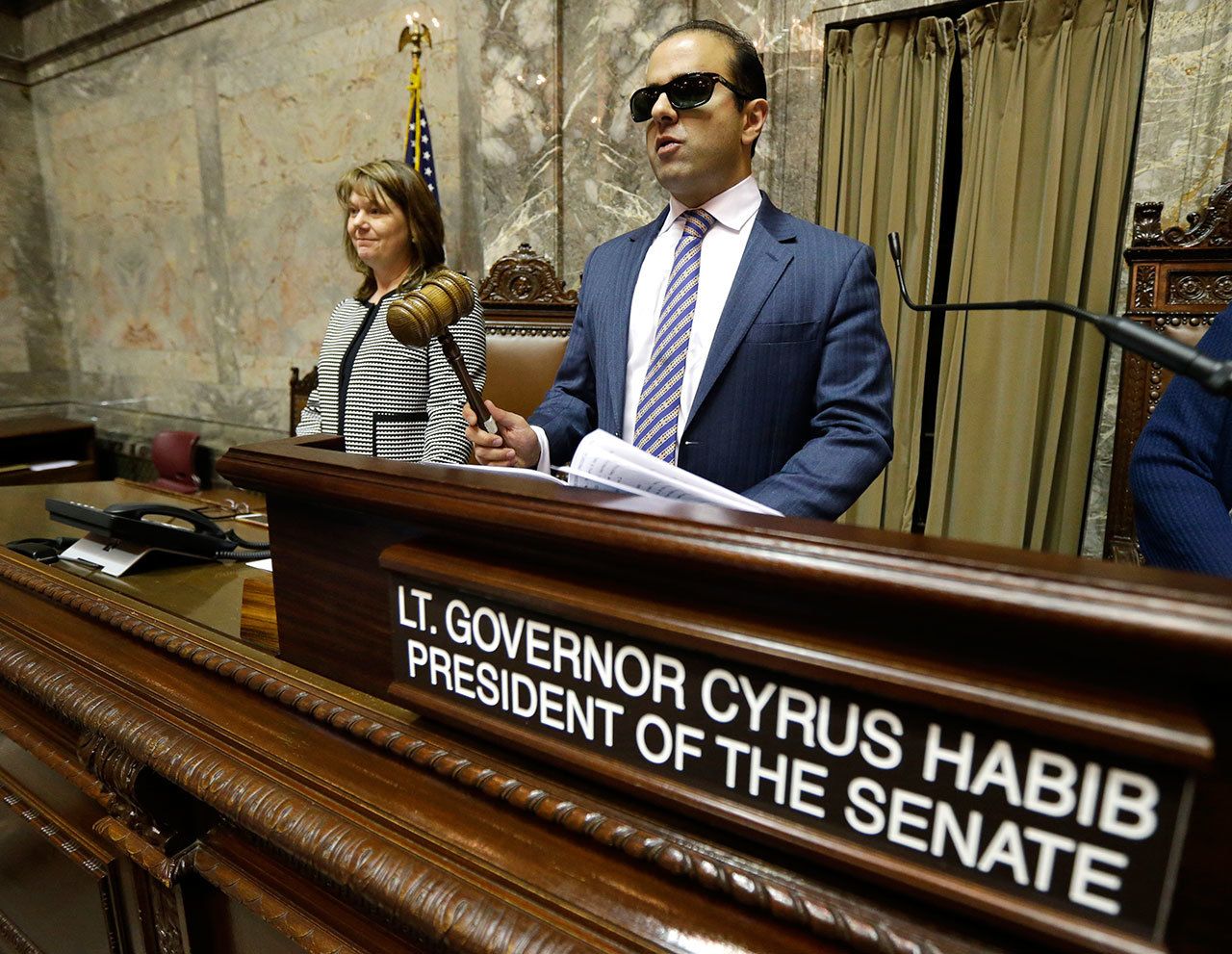Washington Lt. Gov.-elect Cyrus Habib, right, holds the gavel as he stands at the Senate chamber dais next to Senate Counsel Jeannie Gorrell, left, during a practice session to test technical equipment in Olympia last week. (Ted S. Warren/The Associated Press)