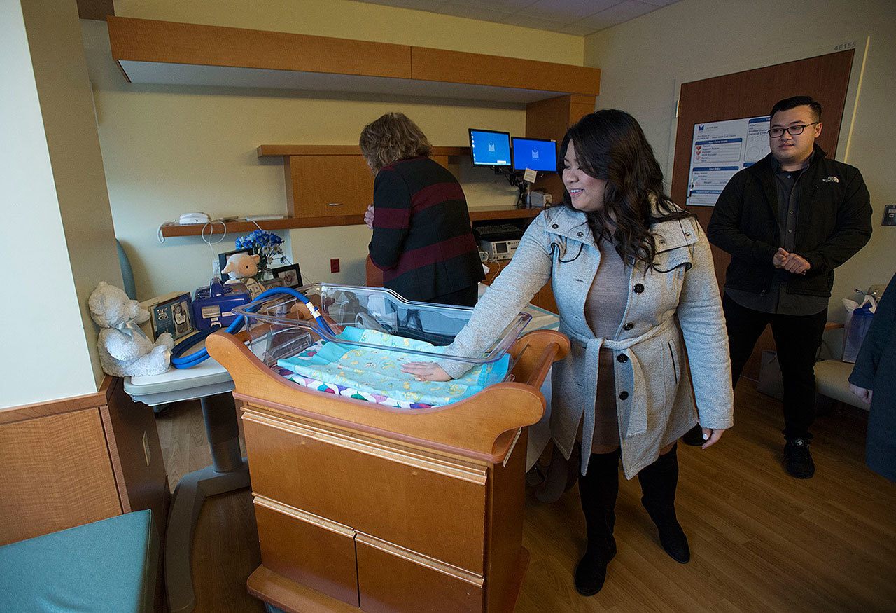 Linda Nguyen, center, looks over the CuddleCot with volunteer services manager Laura Walsh, left, and her fiance, Sonny Mouy, at Legacy Salmon Creek Medical Center in Vancouver, Wash., on Dec. 19, 2016. (Amanda Cowan/The Columbian via AP)