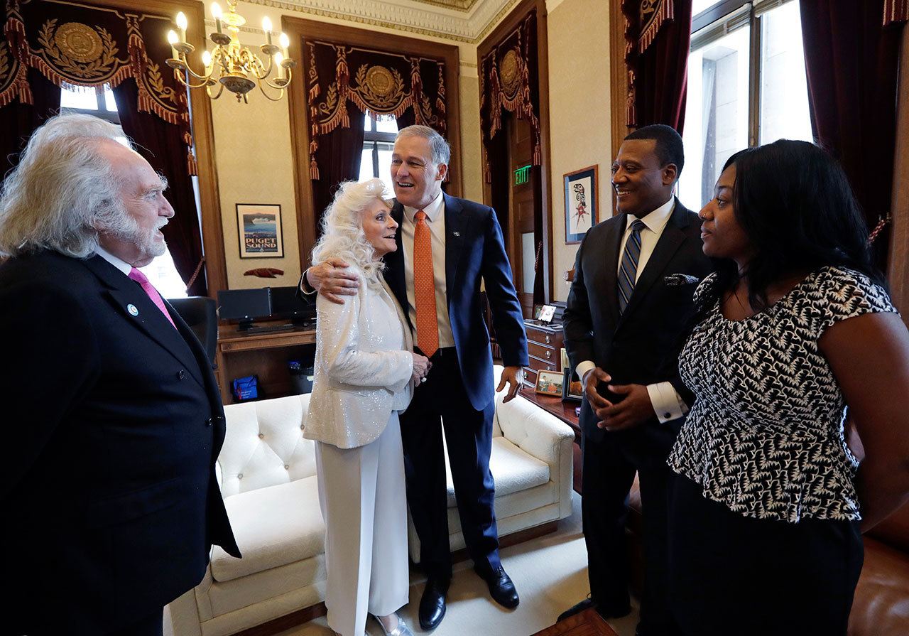 Gov. Jay Inslee embraces singer Judy Collins as they meet before his inaugural address to a joint session of the state Legislature on Wednesday in Olympia. Looking on are Collins’ husband, Louis Nelson, left; the Rev. Leslie Braxton; and Braxton’s daughter, Karissa Braxton. Collins sang the national anthem and Braxton provided the invocation. (Elaine Thompson/The Associated Press)