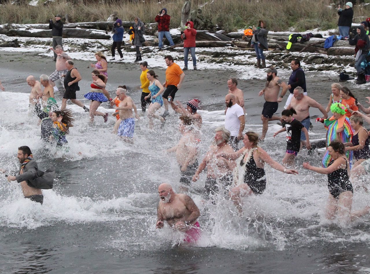 Participants in the 29th annual polar bear plunge in downtown Port Angeles rush into the water at Hollywood Beach on Sunday morning. (Dave Logan/for Peninsula Daily News)