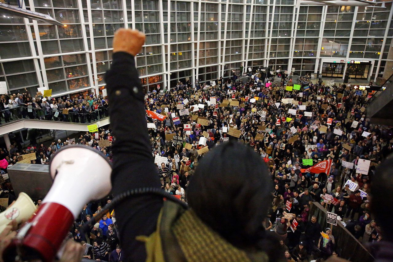 Seattle city councilwoman and socialist activist Kshama Sawant raises a fist over the crowd Saturday as more than 1,000 people gather at Seattle-Tacoma International Airport to protest President Donald Trump’s order that restricts immigration to the U.S. (Genna Martin/seattlepi.com via AP)