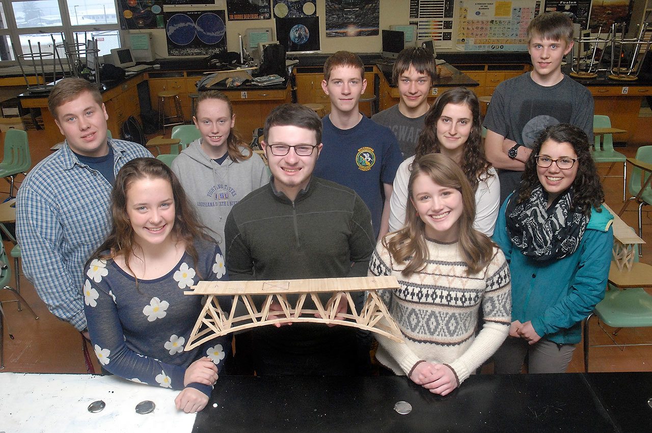 Popsicle bridge contest winners, front row from left, Bonnie Sires, Owen Nevaril and Lauren Rankin, display their winning bridge Wednesday at Port Angeles High School. Also pictured are, second row from left, second-place team Ryan Amiot, Brynn Clark and Drake Anderson, and third-place team Maya Wharton and Lael Butler. A fourth team, who entered the contest with an unofficial bridge, back row from left, Andrew Baker and Matt Lasher, were awarded with scholarship money for their bridge after it took the third-highest load during the contest. (Keith Thorpe/Peninsula Daily News)
