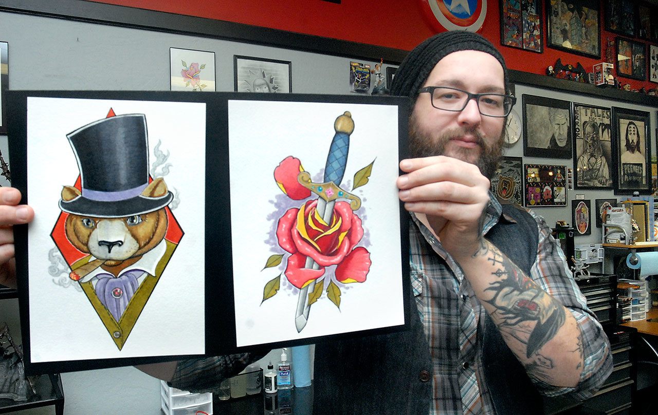 Tattoo artist Russ Brown of Mark’d Body Art in Port Angeles displays samples of his work on Tuesday. (Keith Thorpe/Peninsula Daily News)
