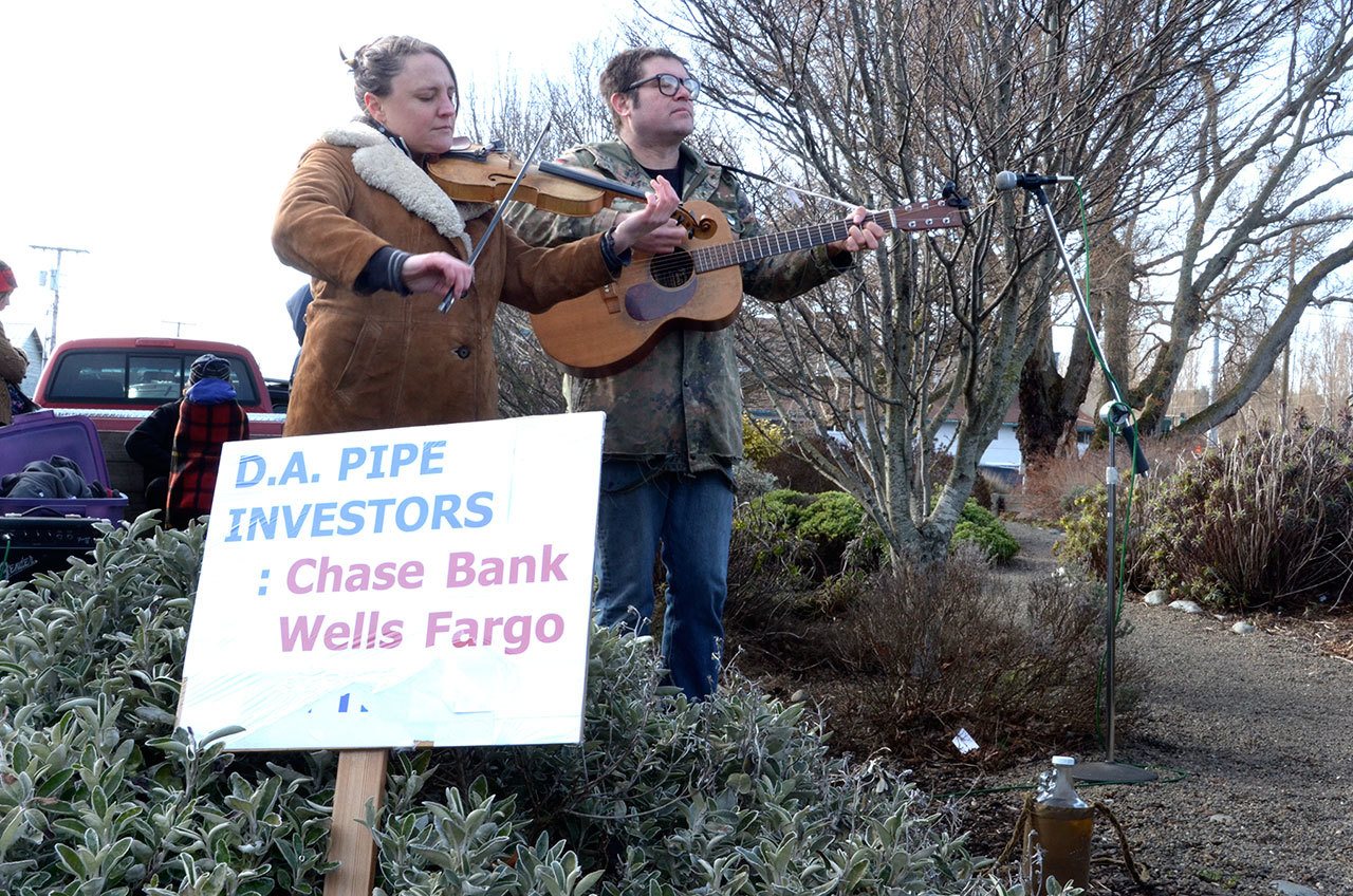 Emily Madden and Jarrod Bramson of the band Solvents play music at a protest against the Dakota Access Pipeline outside of the Port Townsend Wells Fargo on Saturday. (Cydney McFarland/Peninsula Daily News)
