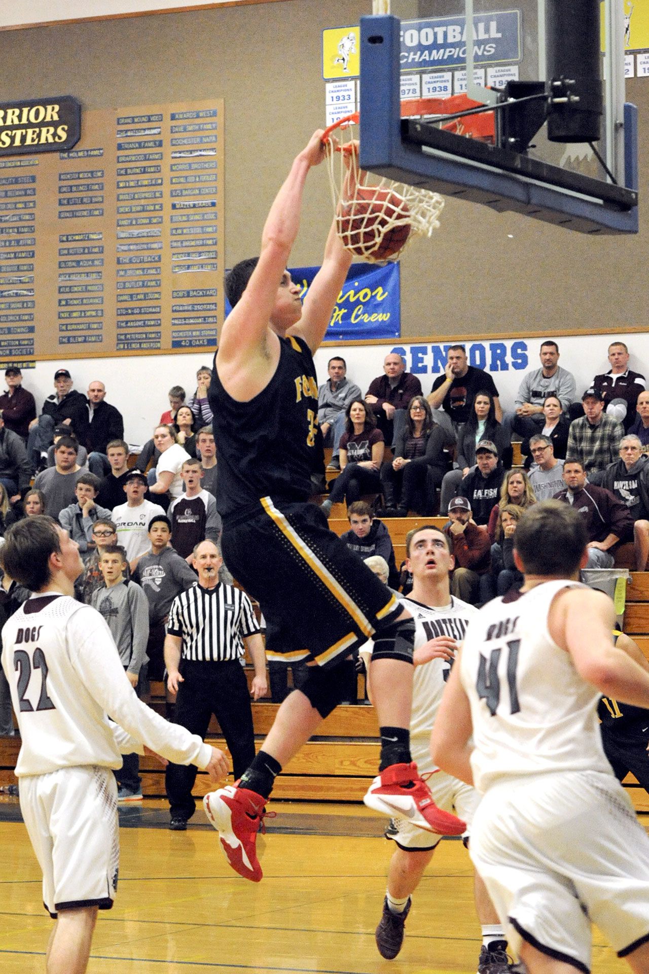 Lonnie Archibald/for Peninsula Daily News Forks’ Marky Adams dunks over Montesano’s Nick Chapman (22), L.J. Valley (32), and Seth Dierkop (41) during teh Spartans’ Class 1A Southwest District 4 Tournament victory. Forks defeated the Bulldogs to move on to a winner-to-state regionals contest against La Center tonight in Chehalis.