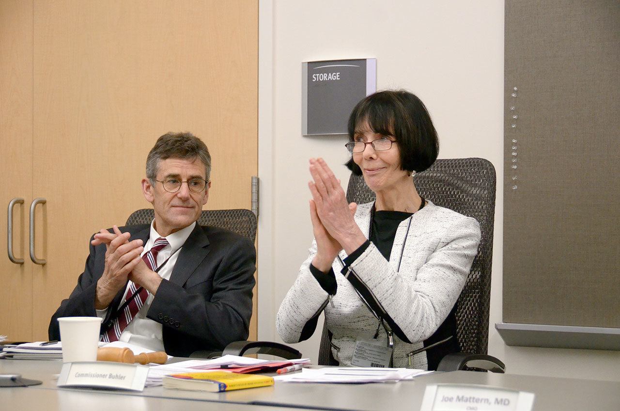 Jefferson Healthcare Commissioner Jill Buhler and hospital CEO Glenn Mike Glenn applaud the hospital commissioners decision to begin the hospitals affiliation with Discovery Behavioral Health at a meeting Wednesday. (Cydney McFarland/Peninsula Daily News)