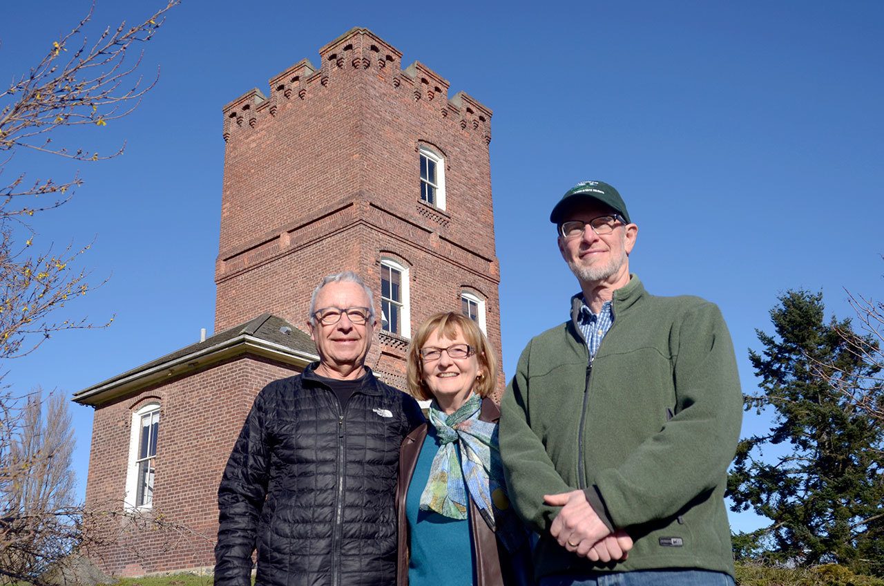 Friends of Fort Worden Secretary Terry LeLievre, President Zan Manning and board member Claude Manning stand in front of Alexander’s Castle, a Fort Worden landmark and the chosen logo of the Friends of Fort Worden, a volunteer organization that works to better the local state park. (Cydney McFarland/Peninsula Daily News)