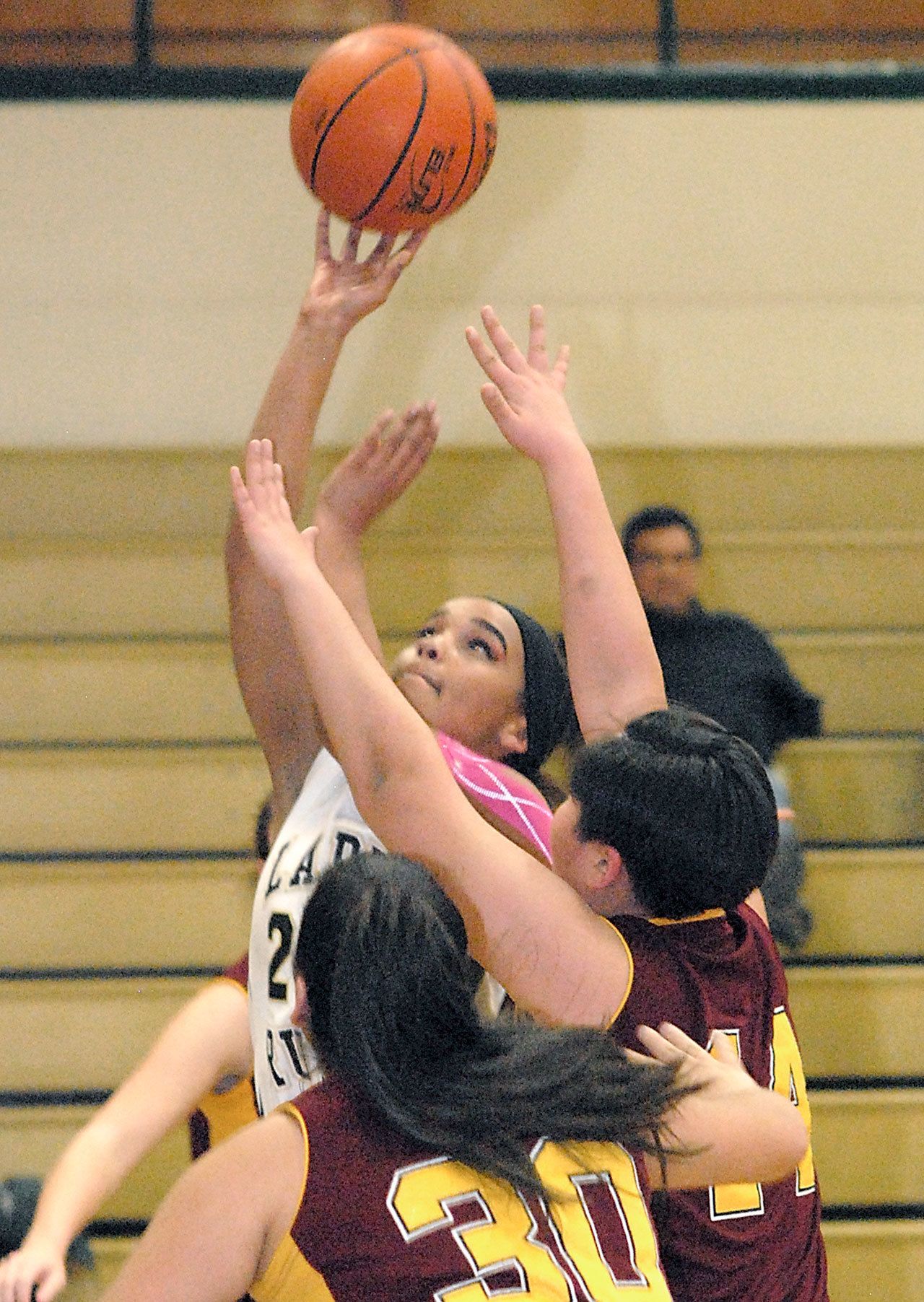 Keith Thorpe/Peninsula Daily News Clallam Bay’s Atokena Abe, top, makes a layup over the defense of Lopez Island’s Anna Velazquez, front, and Dariya Begman during a playoff game played Feb. 14 in Port Angeles.
