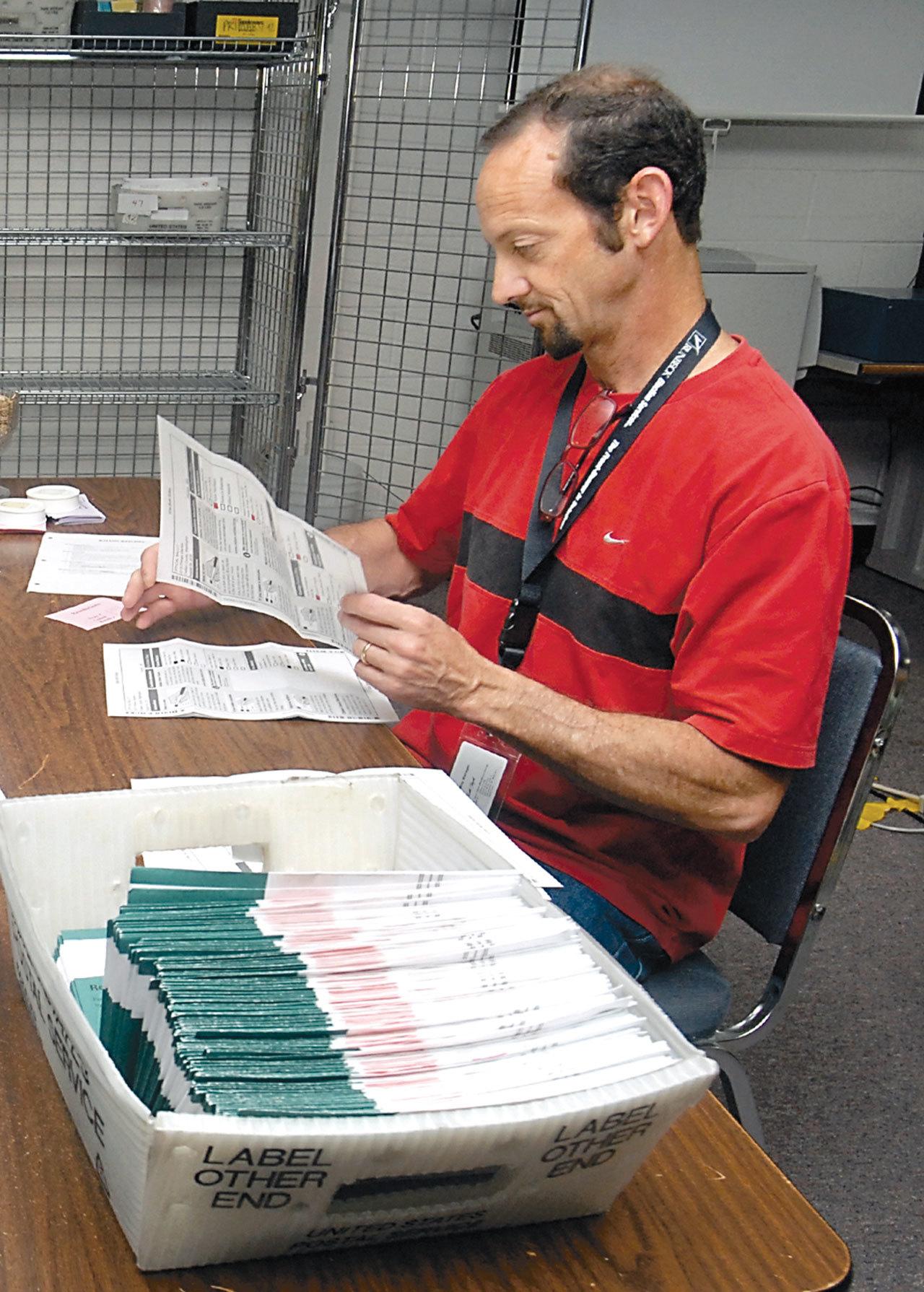 Clallam County Elections Supervisor Ken Hugoniot inspects ballots in August 2015 at the Clallam County Courthouse in Port Angeles. (Keith Thorpe/Peninsula Daily News)