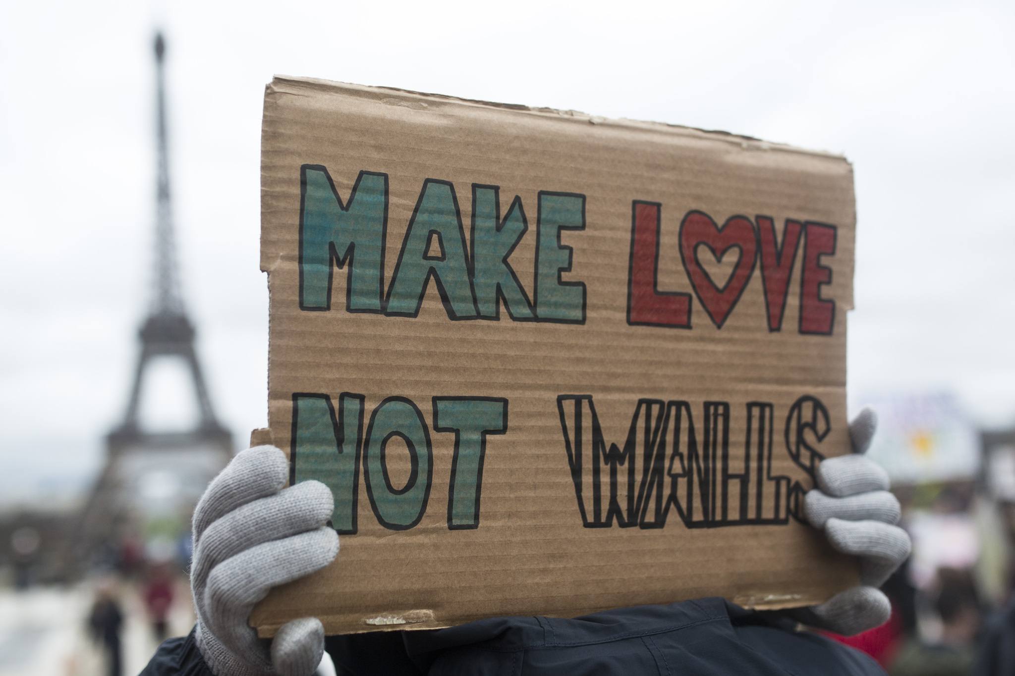 A woman holds a banner reading &ldquo;Make love not walls&rdquo; during a gathering Saturday at Trocadero Plaza next to the Eiffel Tower in Paris to protest U.S. President Donald Trump&rsquo;s recent travel ban to the U.S. (Kamil Zihnioglu/The Associated Press)