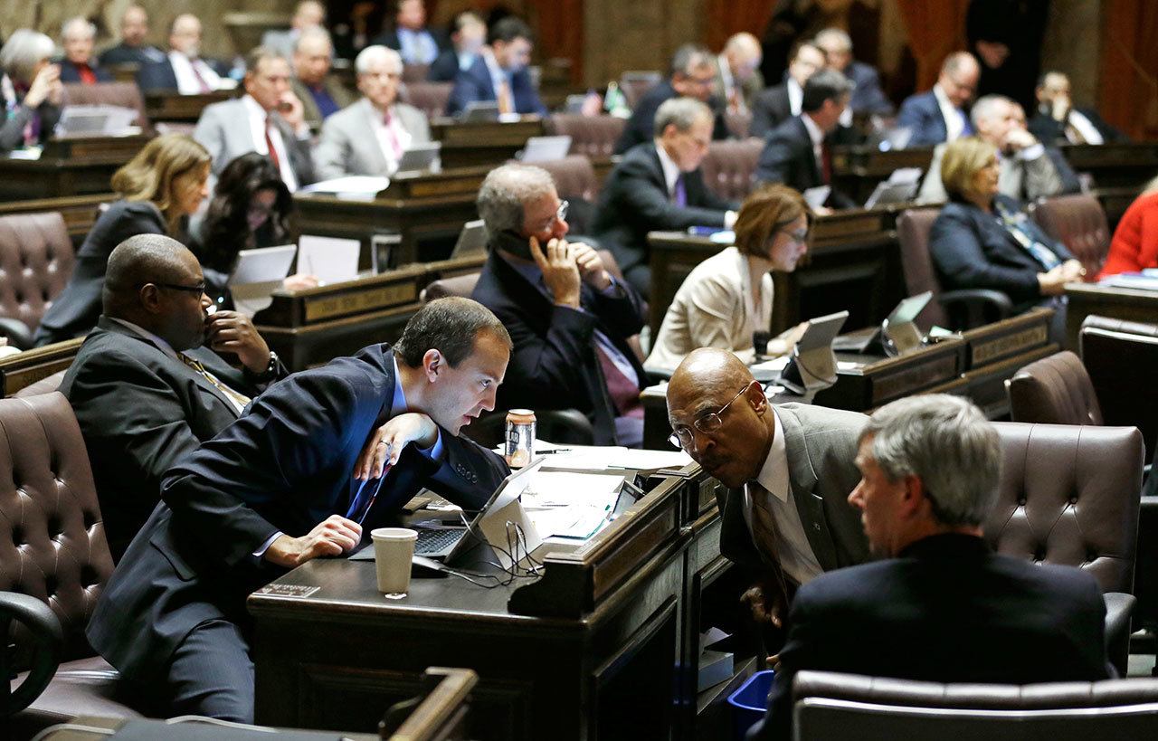 Rep. Marcus Riccelli, D-Spokane, center left, and Rep. John Lovick, D-Mill Creek, center right, confer on the House floor Wednesday during debate over education funding at the Capitol in Olympia. (Ted S. Warren/The Associated Press)