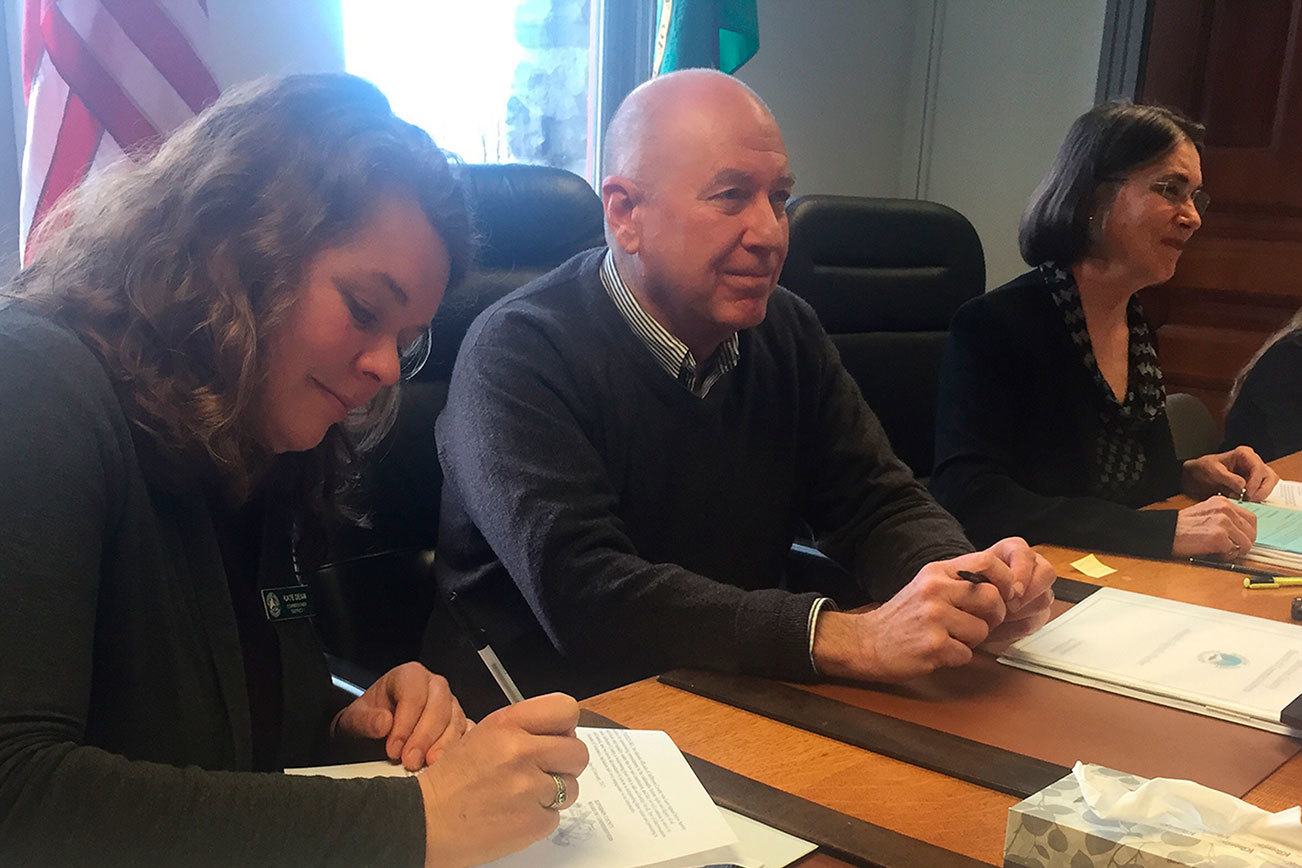 Jefferson County commissioners Kate Dean, David Sullivan and Kathleen Kler sign a human rights proclamation for Jefferson County at their meeting Monday morning. (Cydney McFarland/Peninsula Daily News)