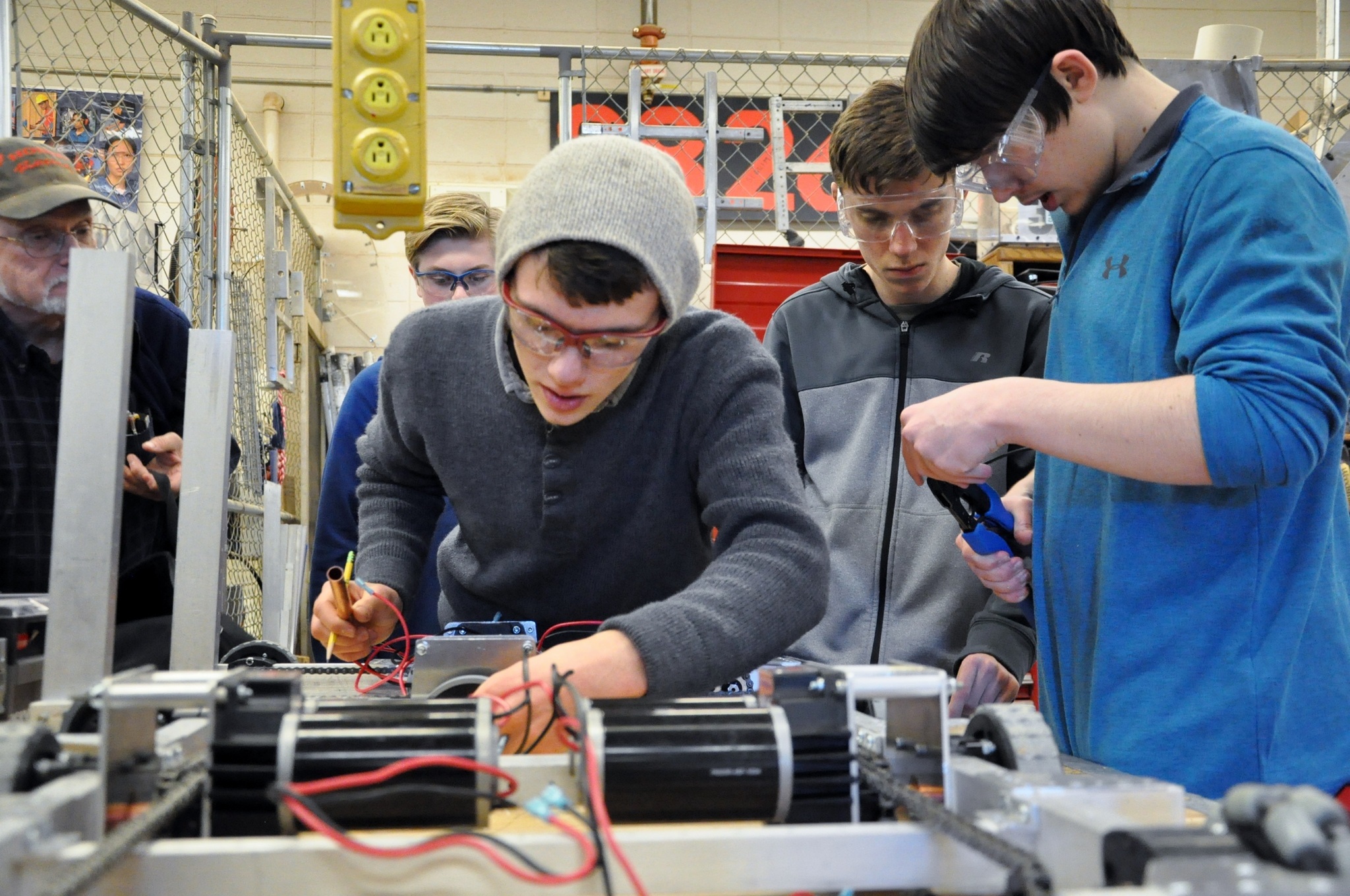 Sequim High School Robotics student Liam Byrne, foreground, works on a component of the robotic chassis, assisted by volunteer mentor Jerry Bileck, Brenton Barnes, Riley Scott and Riley Chase, from left. (Patsene Dashiell)