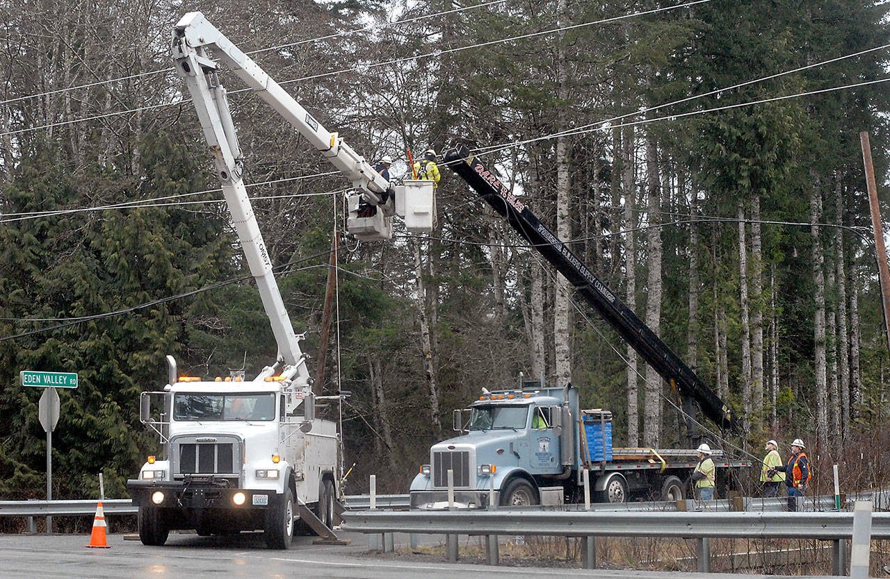 A crew from the Clallam County Public Utility District works to free the conveyor boom from a building supply truck from power lines along state Highway 112 at Eden Valley Road west of Port Angeles on Tuesday. (Keith Thorpe/Peninsula Daily News)