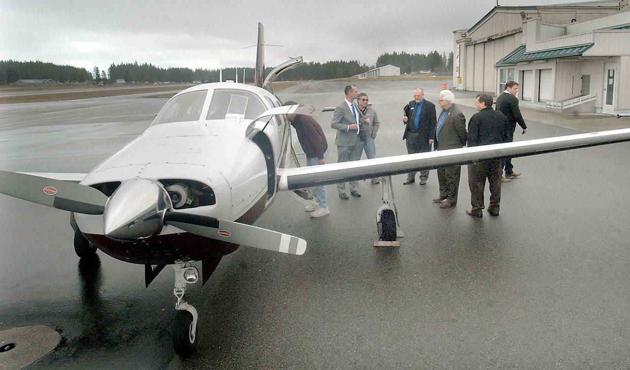 Chris Dupin, chief financial officer for Zephyr Air, center left, talks with North Olympic Peninsula business leaders next to a Piper PA-46 Malibu aircraft belonging to the airline during a promotional visit to William R. Fairchild International Airport in Port Angeles in February. (Keith Thorpe/Peninsula Daily News)