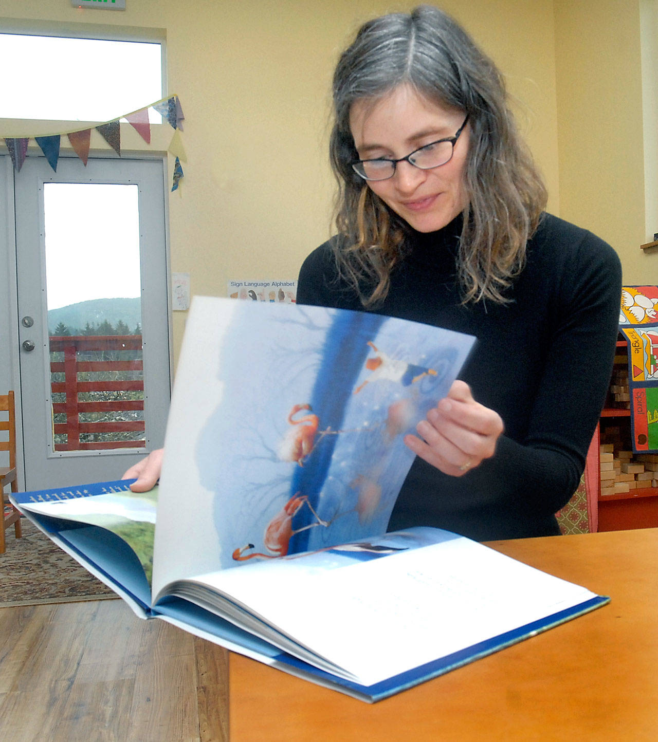 Bonnie Schmidt of Port Angeles leafs through “Wherever You Are, My Love Will Find You” by Nancy Tillman, a book that helped inspire Schmidt’s “Love Sparkle the World” project to promote world change through reading. (Keith Thorpe/Peninsula Daily News)