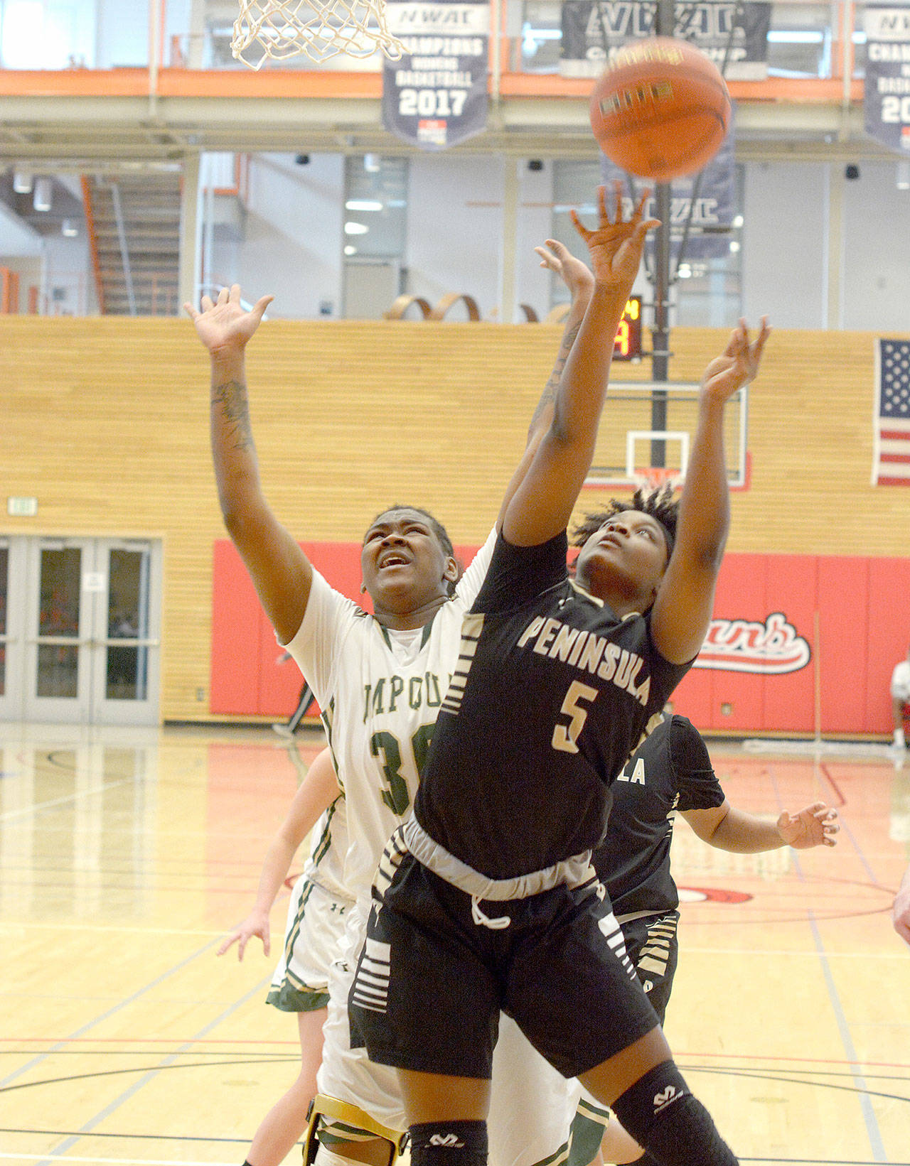Rick Ross/for Peninsula Daily News Peninsula’s Jenise McKnight (5) battles for a rebound against Umpqua’s Dajanay Powell in a second-round NWAC Tournament game in Everett on Sunday.