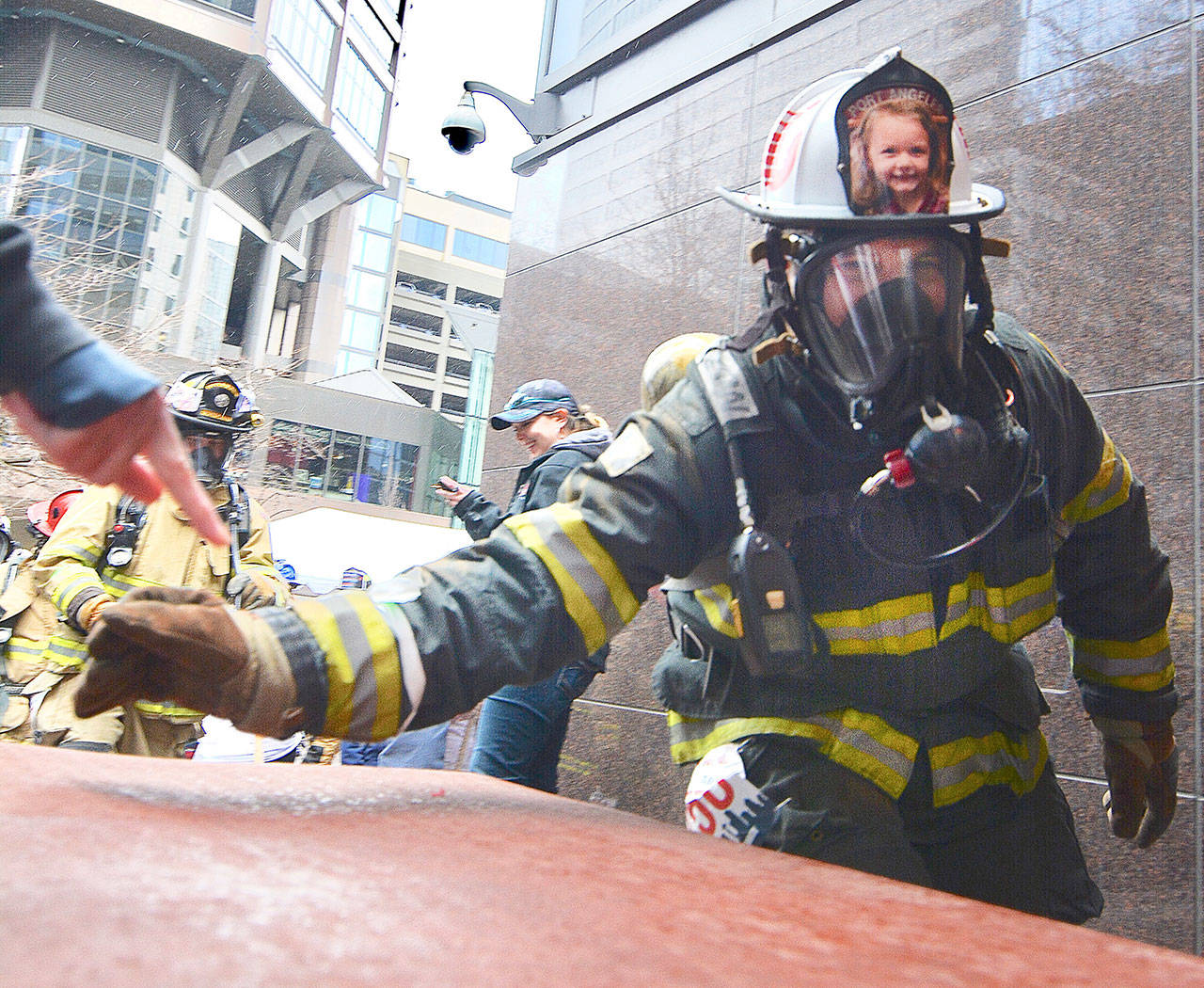 Port Angeles Fire Department firefighter Dan Montana waves his wristband timing chip over a timing mat as he starts his climb up the tower. Picture on his helmet is of Jocelin Hough of Sequim, who is battling acute lymphocytic leukemia. (Jay Cline)