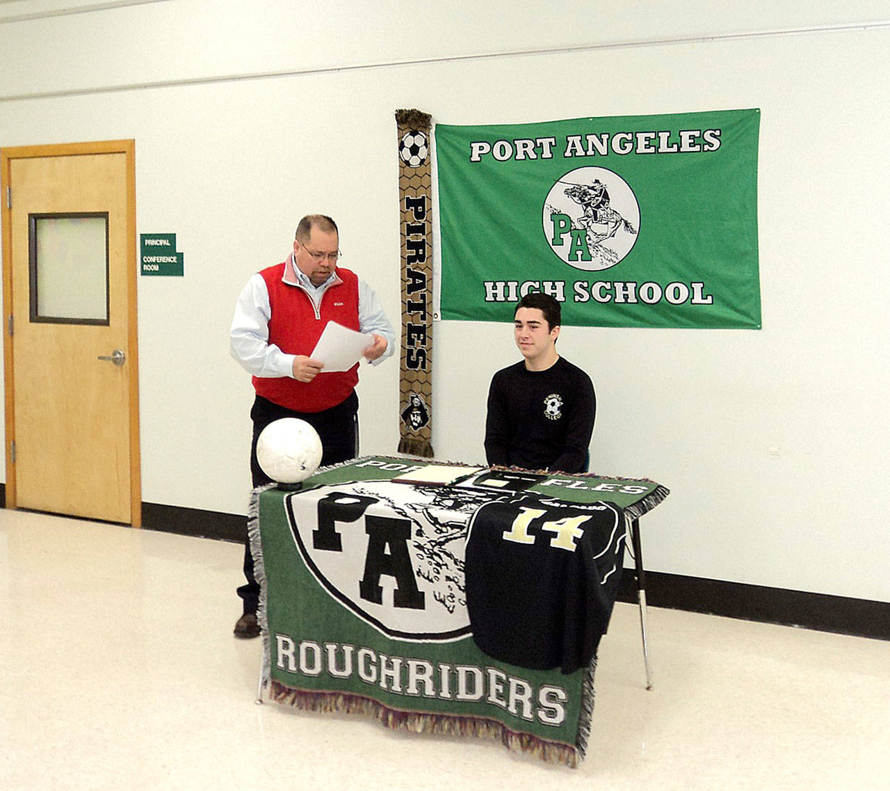 Pierre LaBossiere/Peninsula Daily News Port Angeles student-athlete Jesse Salgado prepares to sign paperwork from Port Angeles Athletic Director Dwayne Johnson to play soccer for the Peninsula College Pirates.