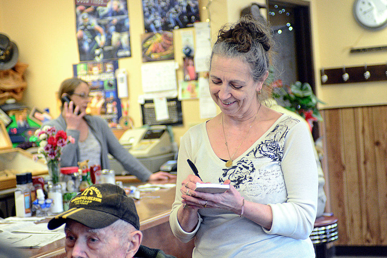 Roxanne Olsen, who owns the Blackberry Cafe in Joyce, takes orders from some of her regular customers Wednesday morning. (Jesse Major/Peninsula Daily News)
