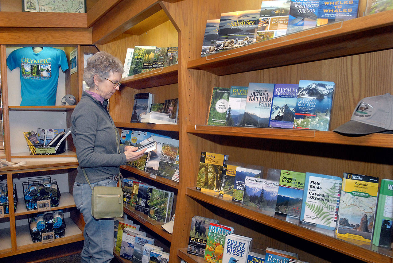 Karen Tallman of Sequim looks over a collection of books about Olympic National Park and the environs of the Pacific Northwest on Friday at the park’s visitor center in Port Angeles. (Keith Thorpe/Peninsula Daily News)