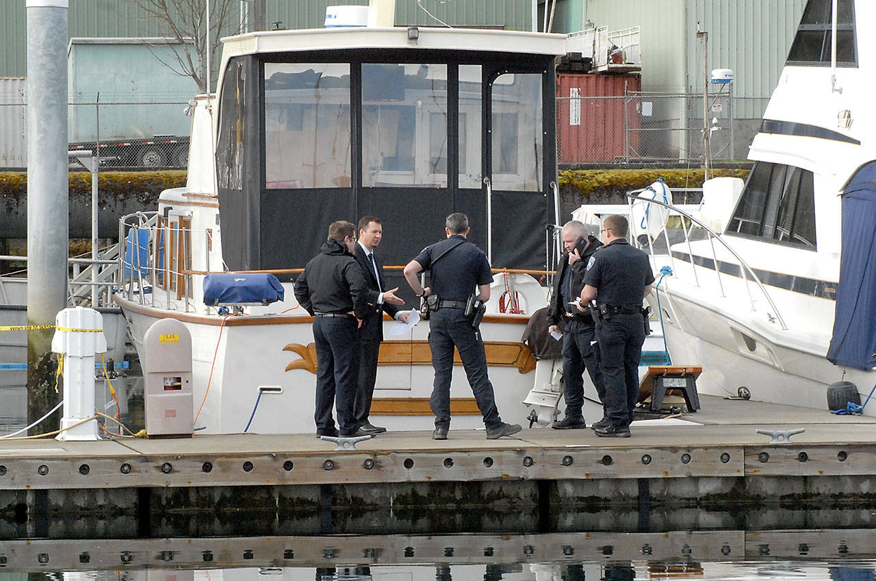 Port Angeles police investigators confer with Clallam County coroner Mark Nichols, second from left, after the body of a man was found floating in the water at Port Angeles Boat Haven on Wednesday morning. (Keith Thorpe/Peninsula Daily News)