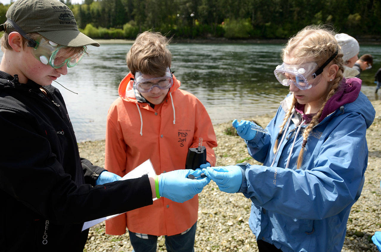 Cydney McFarland (2)/Peninsula Daily News                                 Blue Heron eighth-graders Odin Smith, Andru Goodlin and Gracie Hoffman study water samples taken from the south end of Indian Island for a class project Thursday. Below, Olivia Mattern documents the finding of her group’s phosphate test on the water.