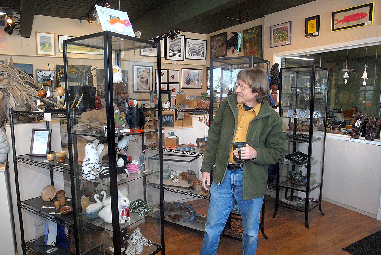 Port Angeles photographer Eric Neurath examines a display case containing works created by a consortium of area artists who operate the Harbor Art Gallery at 110 Railroad Ave., one of several businesses that would be displaced by the construction of a proposed hotel by the Lower Elwha Klallam Tribe. (Keith Thorpe/Peninsula Daily News)