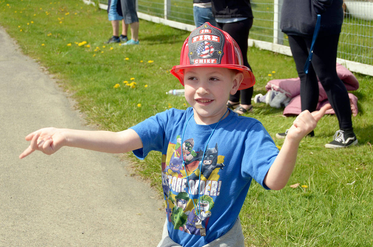 Kiedis Wong of Quilcene waves at the Quilcene Fire Rescue firetrucks that came out for the Brinnon Loyalty Day parade Friday. (Cydney McFarland/Peninsula Daily News)