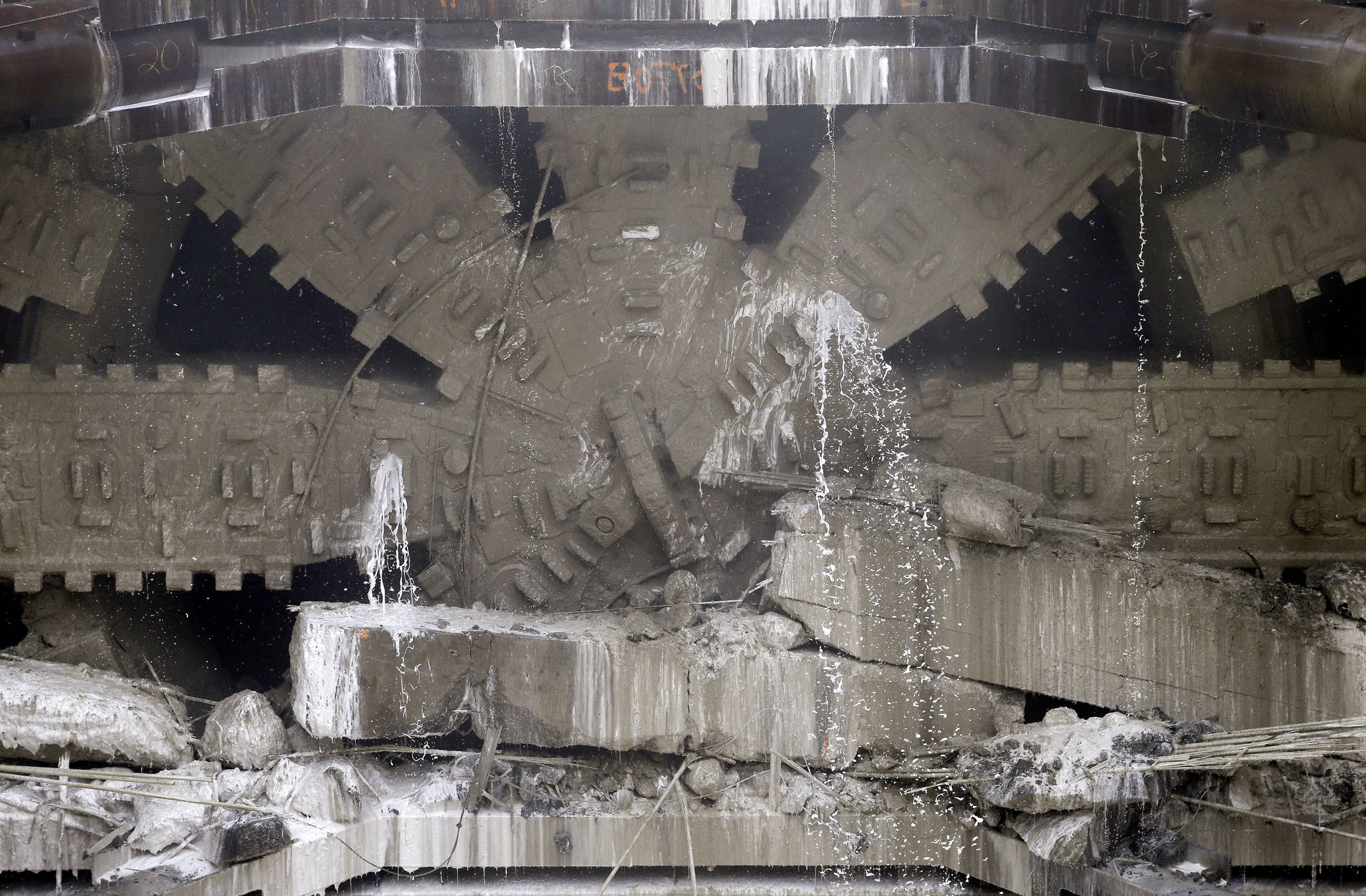 Water cascades from the blades of a massive tunneling machine as it breaks through a 5-foot concrete wall while completing boring for the state Highway 99 route Tuesday under Seattle. (Elaine Thompson/The Associated Press)